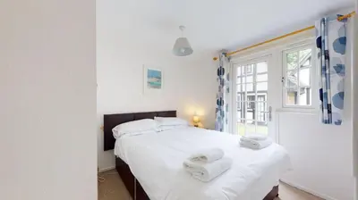 a bedroom with a large white bed with towels on it at 28 Tudor Court, Tolroy Manor in Hayle