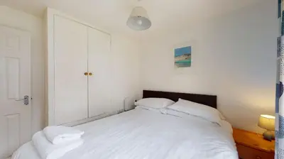 a bedroom with a white bed with white pillows at 28 Tudor Court, Tolroy Manor in Hayle