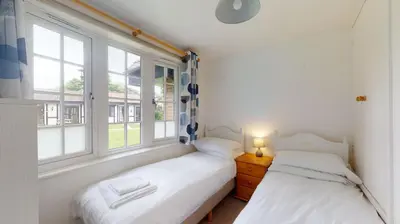 two beds in a room with two windows at 28 Tudor Court, Tolroy Manor in Hayle
