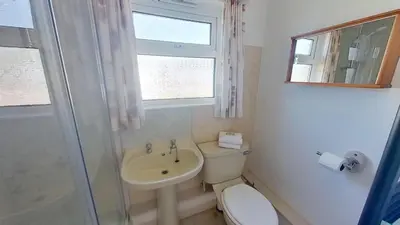a bathroom with a toilet and a sink and a window at D01 Vale Vue D1, Riviere Towans in Hayle
