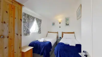 two beds in a room with blue and white sheets at D14 Ridgeway, Riviere Towans in Hayle