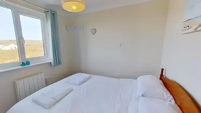 a white bed in a room with a window at D20 Glendon, Riviere Towans in Hayle