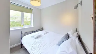 a white bed in a bedroom with a window at D29 Westbourne, Riviere Towans in Hayle