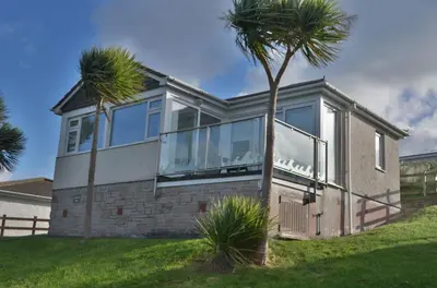 a house with large windows and a palm tree at D29 Westbourne, Riviere Towans in Hayle