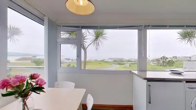 a kitchen with windows and a table with a vase of flowers at D29 Westbourne, Riviere Towans in Hayle