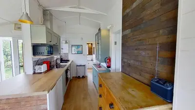 a kitchen with white cabinets and a wooden wall at D04 Hawaiian D4, Riviere Towans in Hayle