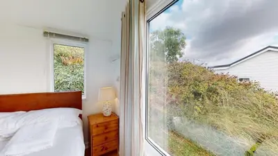 a bedroom with a bed and a large window at D06 Heloan D6, Riviere Towans in Hayle