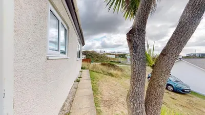 a palm tree next to a house with a car at D06 Heloan D6, Riviere Towans in Hayle