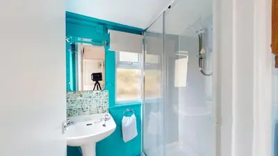 a blue bathroom with a sink and a shower at D06 Heloan D6, Riviere Towans in Hayle