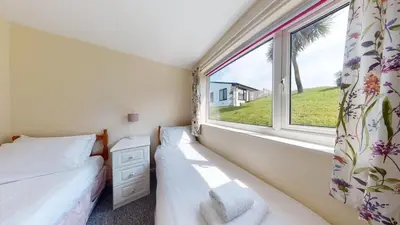 a bedroom with two beds and a window at D32 Chyanvean, Riviere Towans in Hayle