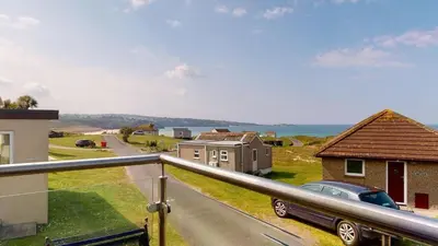 a house with a car parked on the side of a road at D32 Chyanvean, Riviere Towans in Hayle