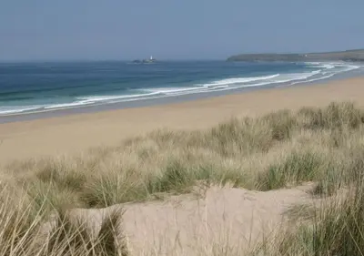 a view of a beach with grass and the ocean at D32 Chyanvean, Riviere Towans in Hayle