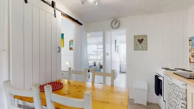a kitchen and dining room with a wooden table at D34 Homeleigh, Riviere Towans in Hayle