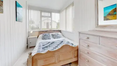 a bedroom with a bed and a dresser and a window at D34 Homeleigh, Riviere Towans in Hayle