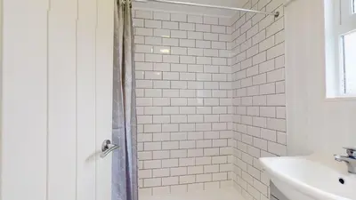 a white tiled bathroom with a shower and a sink at D34 Homeleigh, Riviere Towans in Hayle