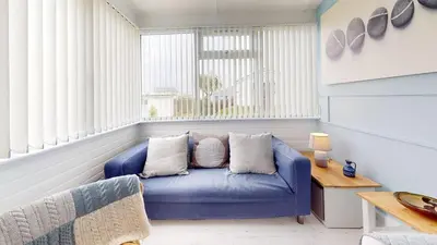 a blue couch in a room with windows at D34 Homeleigh, Riviere Towans in Hayle