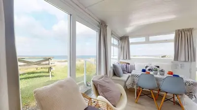 a living room with a table and chairs and a large window at D45 Medina, Riviere Towans in Hayle