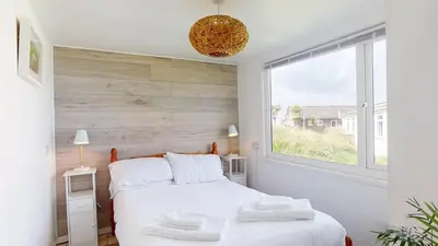 a bedroom with a white bed and a window at D45 Medina, Riviere Towans in Hayle