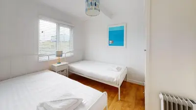 a white room with two beds and a window at D44 Pendarves, Riviere Towans in Hayle