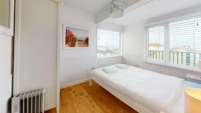 a white bedroom with a bed and two windows at D44 Pendarves, Riviere Towans in Hayle