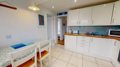 a kitchen with white cabinets and a table and a sink at D44 Pendarves, Riviere Towans in Hayle