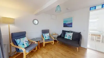 a living room with two chairs and a table at D44 Pendarves, Riviere Towans in Hayle