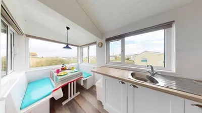 a kitchen with a sink and two windows at D38 Miramar, Riviere Towans in Hayle