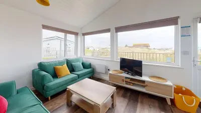 a living room with a green couch and a tv at D38 Miramar, Riviere Towans in Hayle