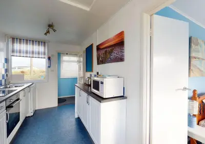 a kitchen with white cabinets and a microwave at D39 St Margarets, Riviere Towans in Hayle