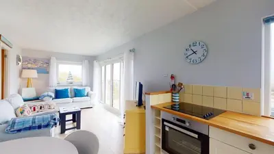 a kitchen and living room with a clock on the wall at D50 Ocean Swell, Riviere Towans in Hayle