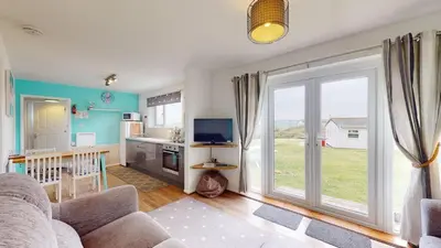 a living room with a kitchen and a large sliding glass door at D52 Boston, Riviere Towans in Hayle