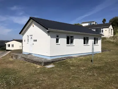 a white house with a black roof in a yard at D52 Boston, Riviere Towans in Hayle