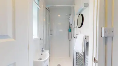a white bathroom with a shower and a sink at D52 Boston, Riviere Towans in Hayle
