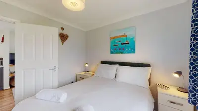 a bedroom with a white bed and a blue curtain at D52 Boston, Riviere Towans in Hayle