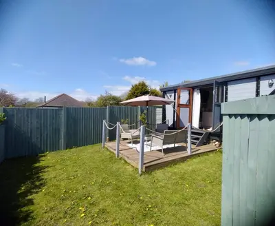 a backyard with a deck with two chairs and an umbrella at Fry’s Carriage in Scorrier
