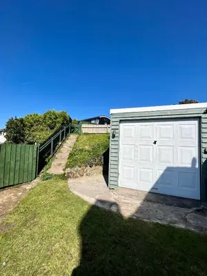 a garage with a white door and a fence at Fry’s Carriage in Scorrier