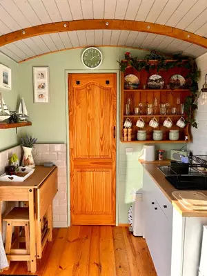 a kitchen with a wooden door and a wooden floor at Fry’s Carriage in Scorrier