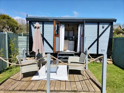 a tiny house with two chairs on a deck at Fry’s Carriage in Scorrier