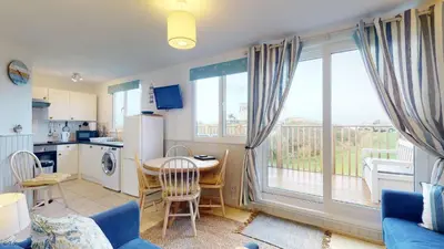 a living room with a table and a kitchen with a window at B07 Sea Esta B7, Riviere Towans in Hayle