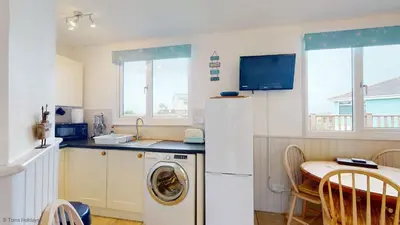 a kitchen with a washing machine and a table at B07 Sea Esta B7, Riviere Towans in Hayle