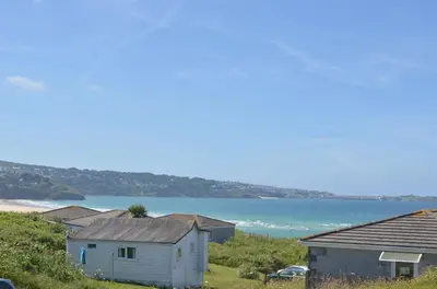 a group of houses on a hill next to a beach at D22 Sandelite, Riviere Towans in Hayle
