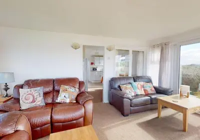 a living room with a leather couch and a table at B42 Shilly Chalet, Riviere Towans in Hayle