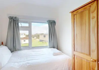 a bedroom with a bed and a large window at B42 Shilly Chalet, Riviere Towans in Hayle