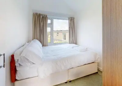 a white bed with a window in a bedroom at B42 Shilly Chalet, Riviere Towans in Hayle