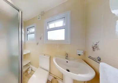 a bathroom with a toilet and a sink and a window at B42 Shilly Chalet, Riviere Towans in Hayle