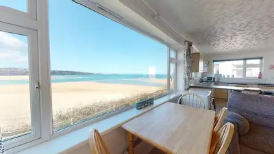 a dining room with a table and a view of the beach at C02 Lanta C2, Riviere Towans in Hayle