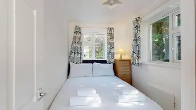 a white bedroom with a bed and two windows at C02 Lanta C2, Riviere Towans in Hayle