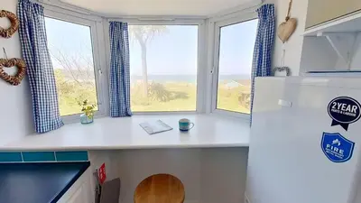 a kitchen with a window and a refrigerator at C17 Sandyridge, Riviere Towans in Hayle