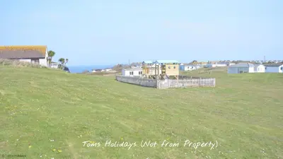 a grassy field with houses on the side of a hill at C17 Sandyridge, Riviere Towans in Hayle