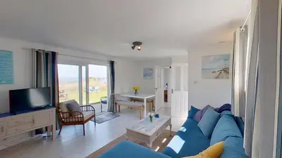a living room with a blue couch and a tv at C17 Sandyridge, Riviere Towans in Hayle